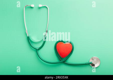 Concept de santé et de mode de vie sain. Vue rapprochée en haut au-dessus de la tête photo d'un stéthoscope noir et d'un petit cœur rouge isolé au-dessus de la table backgrou Banque D'Images