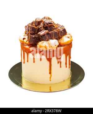 Gâteau délicieux avec glaçage au fromage à la crème caramel salé, meringues et brownie tranché au sommet. Isolé sur fond blanc Banque D'Images