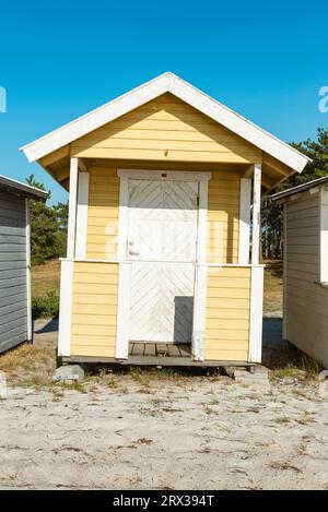 Vue frontale de la façade en bois d'une cabane jaune sur la plage de Skanör med Falsterbo à la Öresund au soleil du soir, Skåne, Suède Banque D'Images