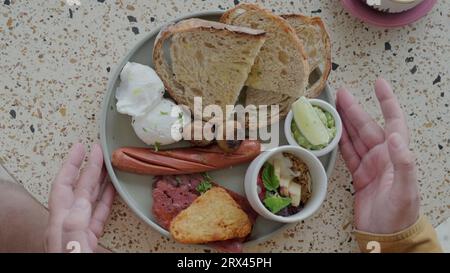 Petit déjeuner britannique traditionnel dans une assiette prise par un homme. Un petit déjeuner en gros plan. Banque D'Images