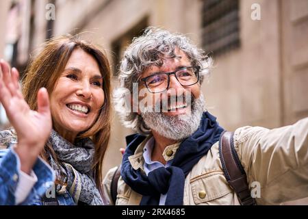 Gros plan d'heureux couple hétérosexuel caucasien mature debout ensemble à l'extérieur saluant un ami. Banque D'Images