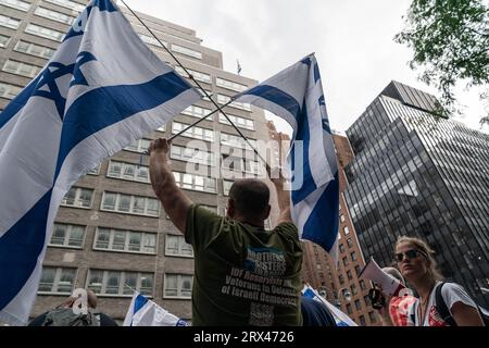 New York, États-Unis. 22 septembre 2023. Des centaines de militants se rassemblent contre les réformes judiciaires proposées par le gouvernement devant la mission israélienne auprès de l’ONU sur la 2e Avenue à New York alors que le Premier ministre Benjamin Netanyahu se rend le 22 septembre 2023. Le rassemblement a eu lieu après le discours prononcé par le Premier ministre lors de la 78e session de l'Assemblée générale des Nations Unies. Drapeau israélien au sommet de la mission vu à travers les manifestants. (Photo de Lev Radin/Sipa USA) crédit : SIPA USA/Alamy Live News Banque D'Images