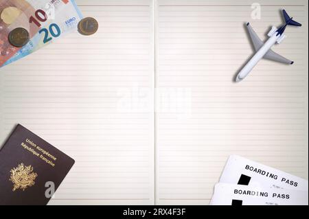 Un passeport français, deux billets d'avion, un avion jouet et quelques euros sur le dessus d'un bloc-notes avec espace de copie. Banque D'Images