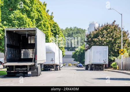 Différents modèles commerciaux des semi-remorques vides de fourgon sec avec porte arrière ouverte debout sur la rue dans la zone industrielle en attente du temps de chargement Banque D'Images