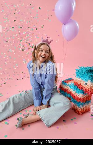 Bonne jeune femme célébrant son anniversaire sur fond rose Banque D'Images