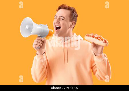 Crier jeune homme avec hot-dog savoureux et mégaphone sur fond jaune Banque D'Images