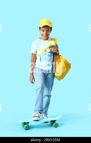 Petit garçon afro-américain avec skateboard sur fond bleu Banque D'Images