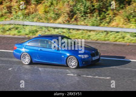 2010 BMW 320D M Sport Auto 181 320D Step Auto Blue car coupe Diesel 1995 cc miroir de la voiture  réflexion du véhicule sur route mouillée ; déplacement à grande vitesse sur l'autoroute M6 dans le Grand Manchester, Royaume-Uni Banque D'Images