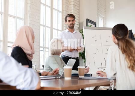 Les membres multiculturels écoutent un orateur confiant lors d'une réunion de groupe dans la salle de conseil Banque D'Images