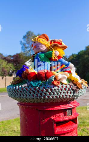 Poole, Dorset, Royaume-Uni. 23 septembre 2023. UK Météo : Sunshine comme un topper de boîte aux lettres crocheté tricoté apparaît sur une boîte aux lettres rouge à Poole, Dorset avec un thème du Festival de la récolte, une célébration de la récolte et de la nourriture cultivée, pour célébrer quand les cultures ont été rassemblées et les gens peuvent réfléchir et montrer de la gratitude pour la nourriture qu'ils ont. Crédit : Carolyn Jenkins/Alamy Live News Banque D'Images