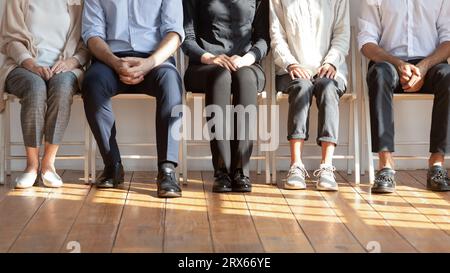 Diverses personnes assises sur des chaises attendent dans la file d'attente de l'entretien d'embauche Banque D'Images