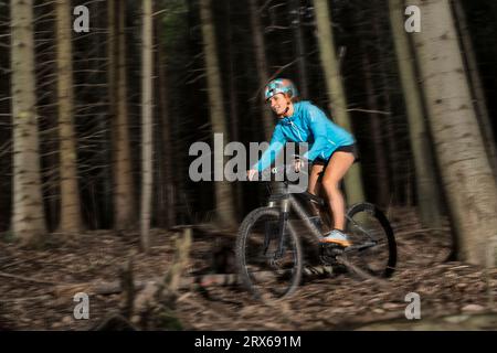 Jeune femme faisant du vélo de montagne à travers la forêt Banque D'Images
