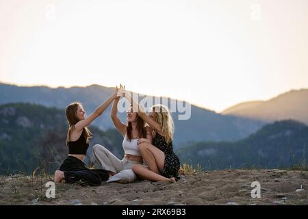 Femmes souriantes se tenant la main et profitant des vacances au coucher du soleil Banque D'Images