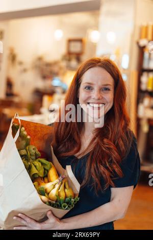 Heureuse femme rousse faisant des courses au magasin Banque D'Images