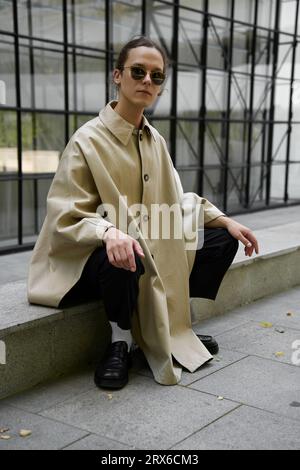 Jeune homme portant des lunettes de soleil assis devant un bâtiment moderne Banque D'Images