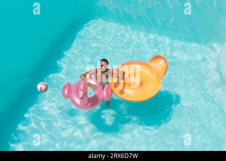 Homme souriant avec flotteurs gonflables de natation dans la piscine Banque D'Images