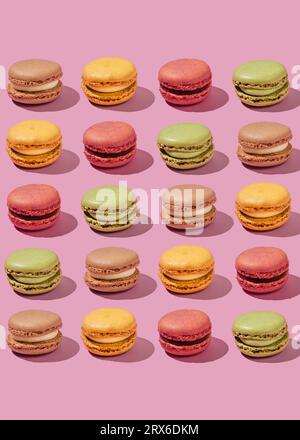 Macarons multicolores disposés sur fond rose Banque D'Images