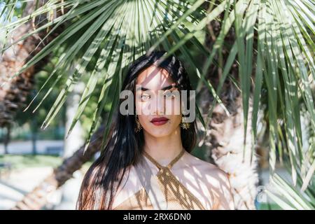 Jeune femme sous des feuilles de palmier vertes Banque D'Images