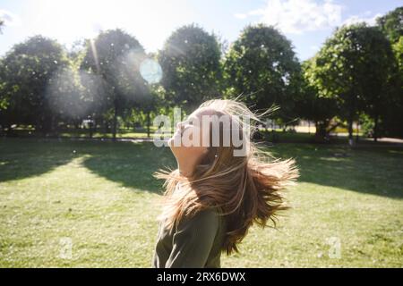 Joyeuse fille blonde appréciant dans le parc sur la journée ensoleillée Banque D'Images
