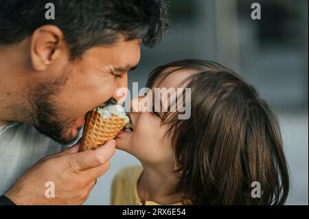 Père et fils partageant la crème glacée ensemble Banque D'Images