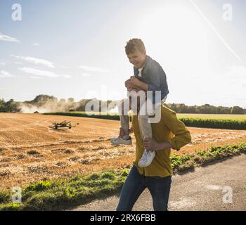 Heureux grand-père portant petit-fils sur les épaules sur la route Banque D'Images