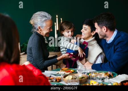 Grand-mère souriante donnant cadeau de Noël à son petit-fils à la maison Banque D'Images