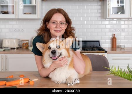 Femme souriante avec chien Welsh Corgi dans la cuisine Banque D'Images