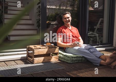 Homme se détendant sur le balcon avec mug à la main Banque D'Images