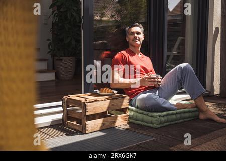 Homme se détendant sur le balcon avec mug à la main Banque D'Images