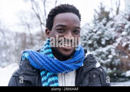 Jeune homme souriant portant une écharpe bleue en hiver Banque D'Images