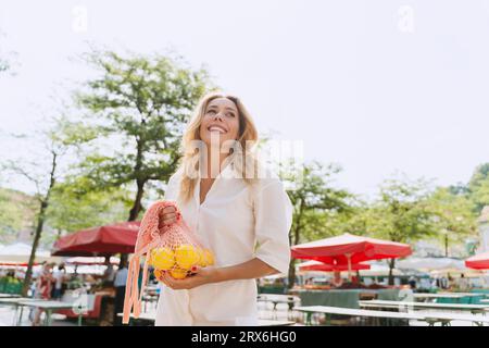 Femme heureuse tenant un sac de citrons sur le marché Banque D'Images