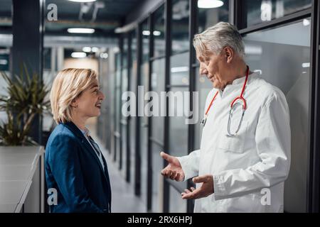 Patient souriant écoutant le médecin parler à l'hôpital Banque D'Images