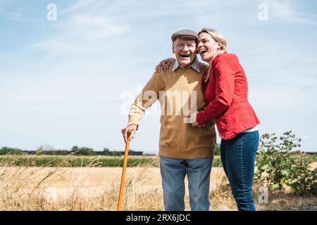 Femme joyeuse embrassant l'homme âgé debout par le champ Banque D'Images