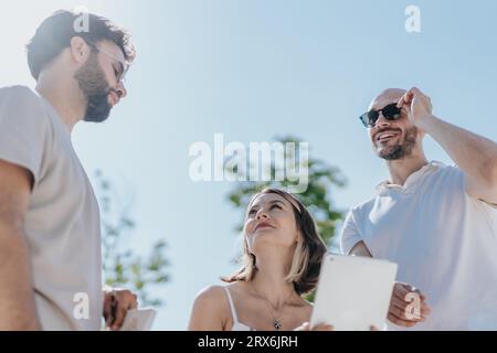 Architectes et ingénieurs créatifs discutent d'un projet de construction en plein air dans une zone urbaine moderne, analysant un plan sur une tablette. Équipe réussie Banque D'Images