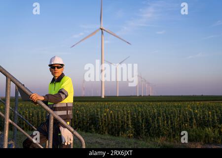 Ingénieur avec ordinateur portable se déplaçant sur des marches par des éoliennes Banque D'Images