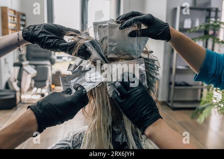 Coiffeurs teintant les cheveux du client dans le salon Banque D'Images