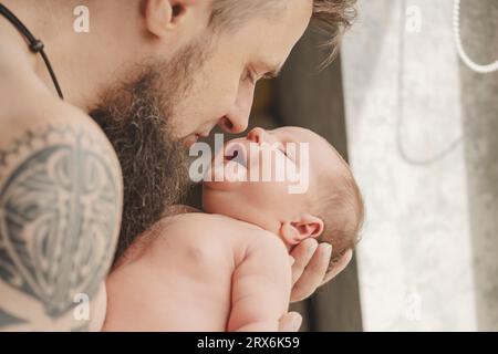 Père avec tatouage sur le bras portant sa fille à la maison Banque D'Images