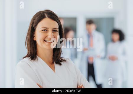 Médecin satisfaite et confiante en clinique, posant avec les bras pliés, portant une blouse de laboratoire. Spécialiste professionnel et performant fournissant des soins de santé s Banque D'Images