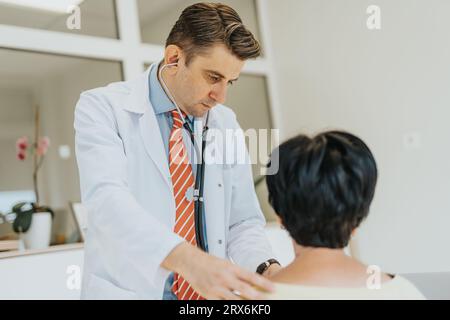 Médecin expérimenté examine le patient, vérifie les signes vitaux, mesure la tension artérielle, discute de la santé, fournit des soins de qualité. Banque D'Images