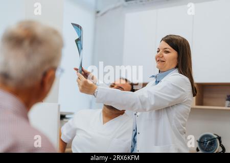 Les médecins examinent les résultats des radiographies dans son cabinet, analysant le film thoracique de la patiente pour les problèmes de santé. La consultation et le diagnostic se déroulent dans le calme Banque D'Images