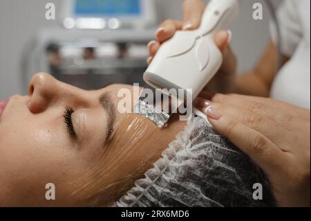 Dermatologue faisant le nettoyage facial ultrasonique sur le visage de la femme Banque D'Images