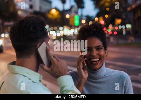 Femme et homme heureux parlant sur les téléphones intelligents Banque D'Images