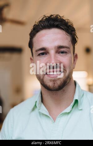 Jeune homme d'affaires souriant avec barbe dans le café Banque D'Images