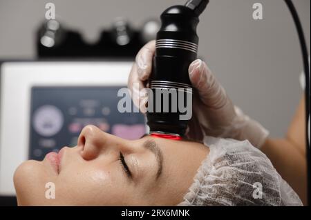 Dermatologue pratiquant un lifting RF sur le visage d'une femme en clinique Banque D'Images