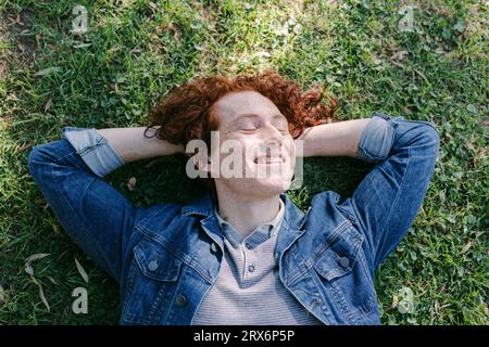 Jeune homme souriant se détendant sur l'herbe Banque D'Images