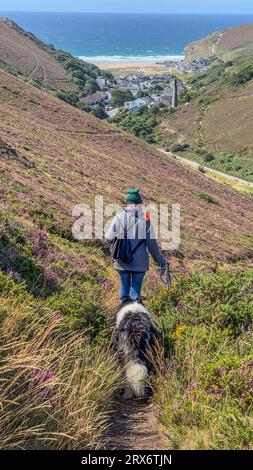 femme avec chien collie de frontière marchant loin de la caméra vers porthtowan, cornwall, uk Banque D'Images