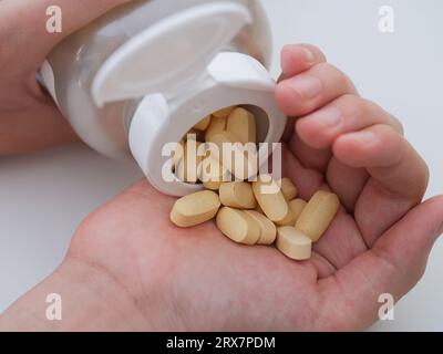 Un jeune homme verse des comprimés de taurate de magnésium d'une bouteille dans la paume de sa main. Gros plan. Banque D'Images