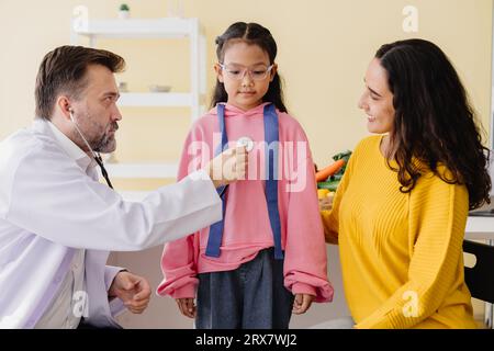 Mère avec fille rencontrant un médecin pédiatre à la clinique pour un bilan de santé parlant de problèmes mentaux. Banque D'Images