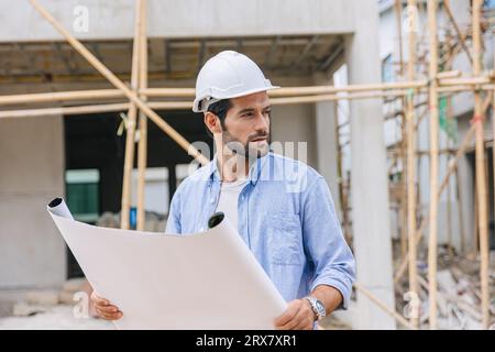 Travaux de constructeur d'ingénieur de construction sur le chantier de construction. Architecte contremaître de projet de maison concepteur en chef travaillant avec le plan d'étage. Banque D'Images