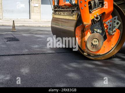 Image d'un tracteur Orange avec cylindre pour revêtement en asphalte sur route Banque D'Images